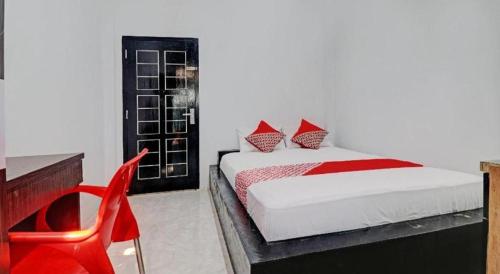 ein Schlafzimmer mit einem Bett und einem roten Stuhl in der Unterkunft Hotel O Al-razzaq Guest House in Jambi
