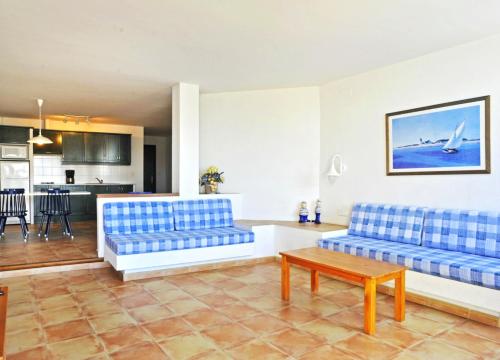 sala de estar con sofás azules y cocina en Apartaments El Berganti en Canyelles Petites en Roses