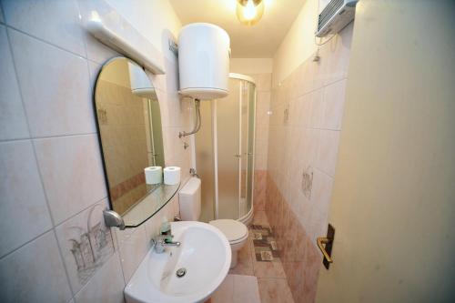 a bathroom with a sink and a toilet and a mirror at Rooms Novaković in Opatija