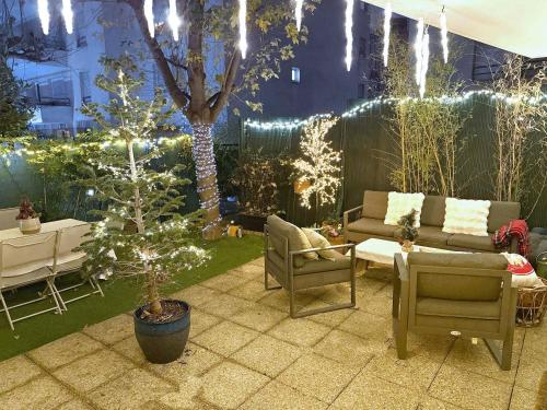 eine Terrasse mit Weihnachtsbaum, Sofa und Stühlen in der Unterkunft Le jardin du stade by UTA HOUSE in Saint-Denis
