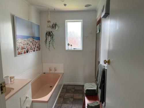 a bathroom with a tub and a sink and a window at Cosy & close to town in Te Anau