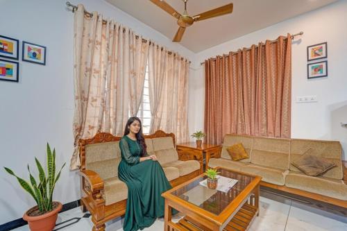 a woman sitting on a couch in a living room at FabHotel Raja Residency in Alāndurai