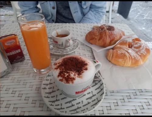einen Tisch mit einer Tasse Kaffee, Croissants und Orangensaft in der Unterkunft Il rifugio di Kekka piazza del plebiscito Napoli in Neapel