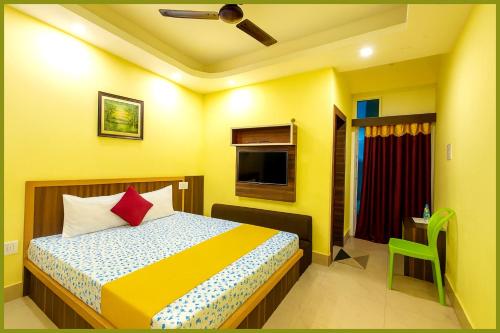 Dormitorio amarillo con cama y TV en Jagannath Temple Shashi Palace Resort - Fully Air conditioned# Free Wifi And Room Service #Budget Class Best Hotel IN Puri, en Puri