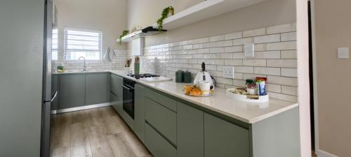 a kitchen with gray cabinets and white tile walls at Black Eagle's Rest #Unit 1-8 in Langebaan