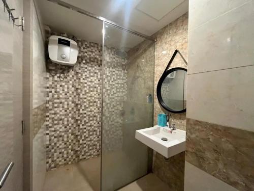 a bathroom with a sink and a shower with a mirror at The Haven Room at Mataram City Apartment - Yudhistira Tower in Kejayan