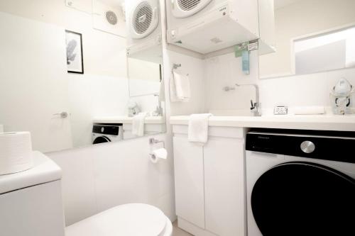 Un baño blanco con inodoro y lavabo. en The Helm Unit 1 22 Voyager Close, en Nelson Bay
