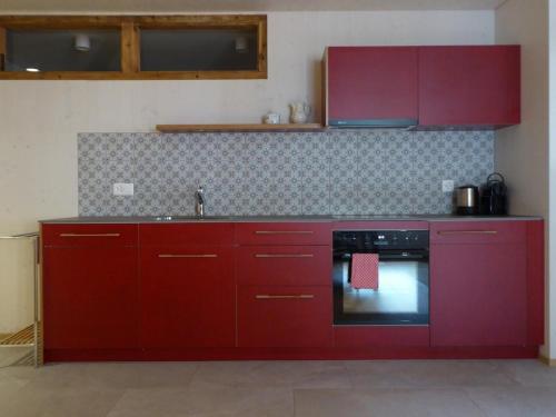 a kitchen with red cabinets and a sink at Biala Biobergün in Bergün