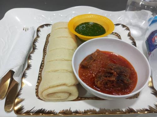 une assiette de nourriture avec un bol de salsa et du pain dans l'établissement Rama Garden Hotel ,Lafe Rd, Akure, à Akure