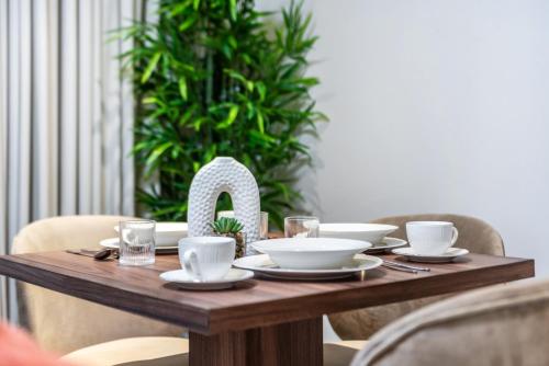 a wooden table with plates and bowls on it at The Living khorfakan Cornish 2 in Khor Fakkan