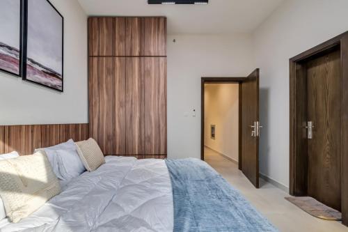 a bedroom with a large bed and a wooden door at 2BR and maidroom khorfakan Cornish 2 in Khor Fakkan