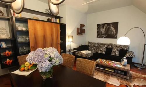 ein Wohnzimmer mit einer Couch und einem Tisch mit Blumen in der Unterkunft Luxury Apartment with Sea View in Malpica, 230 sq.m in Malpica