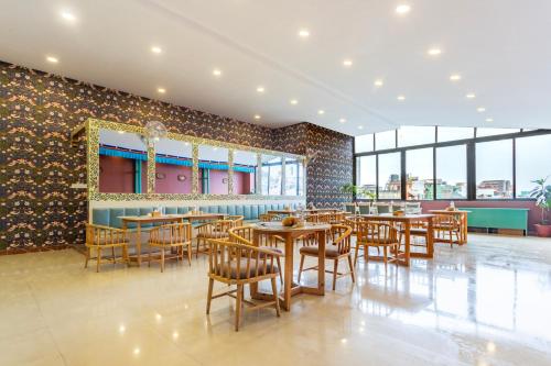 Un restaurante con mesas y sillas de madera y ventanas. en Hotel Yukhang, en Katmandú