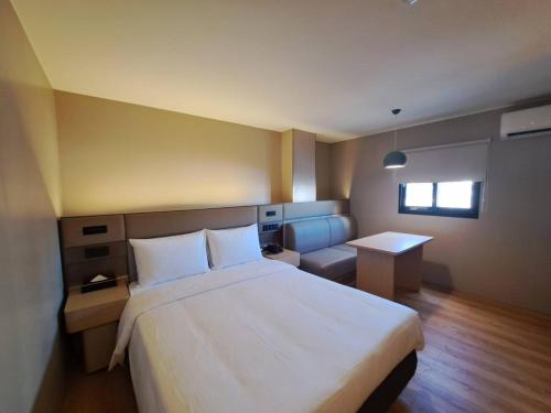 Un dormitorio con una cama blanca grande y un escritorio en 丰居中壢 Via Hotel Zhongli, en Zhongli