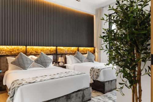 a hotel room with two beds and a plant at Stylish 2 Bedrooms, Pool, Gym & Family-Friendly in Dubai