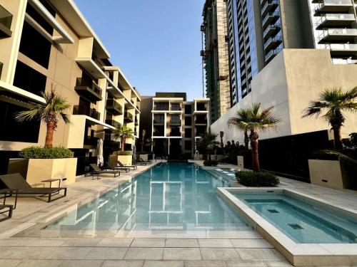 a swimming pool with palm trees and buildings at Stylish 2 Bedrooms, Pool, Gym & Family-Friendly in Dubai