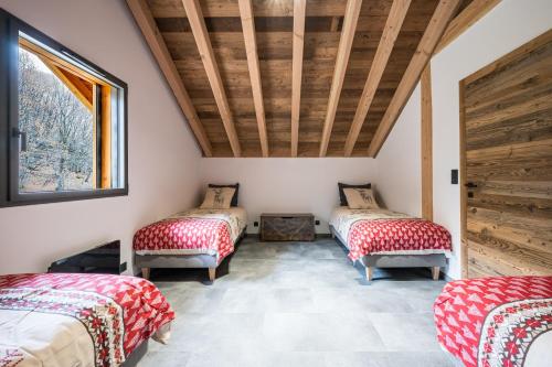 een kamer met 3 bedden en rode en witte dekens bij Chalet l'Orée in Valloire
