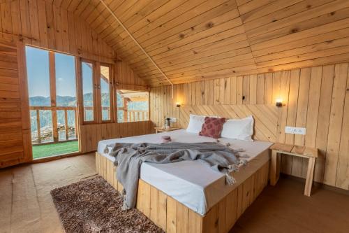 Jufri Hills Cottage في Jibhi: غرفة نوم بسرير كبير في غرفة خشبية