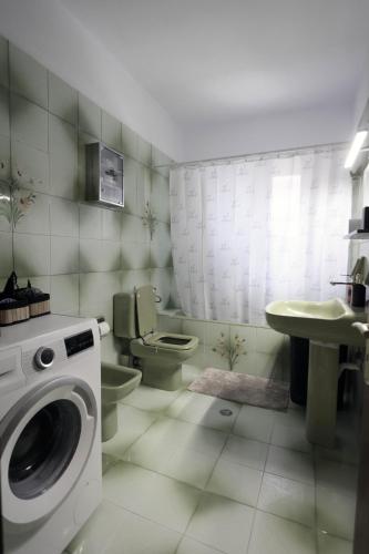 a bathroom with a toilet and a sink and a washing machine at Εν Καρδιά in Ioannina