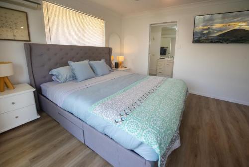 ein Schlafzimmer mit einem großen Bett mit blauen Kissen in der Unterkunft Serene Saltair in Redland Bay