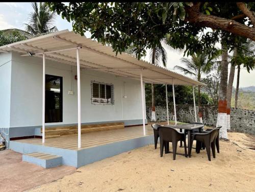 Una casa con una mesa y sillas delante de ella. en Secret Shore N Tide Luxurious Suite , Sea Facing, en Alibaug