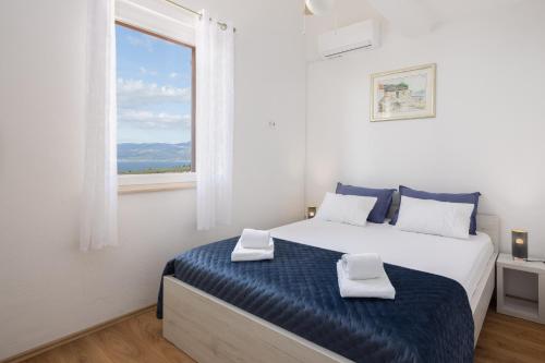 ein weißes Schlafzimmer mit einem großen Bett und einem Fenster in der Unterkunft Villa Fani in Supetar