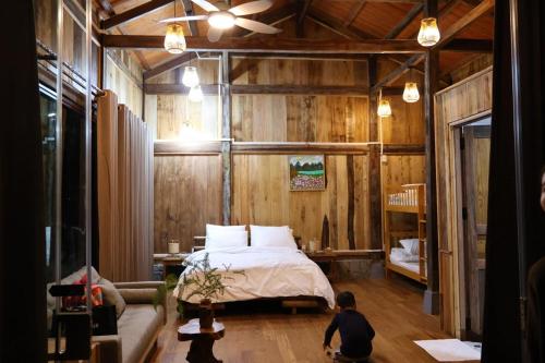 a boy sitting in a bedroom with a bed at Balana HaGiang in Làng Lap