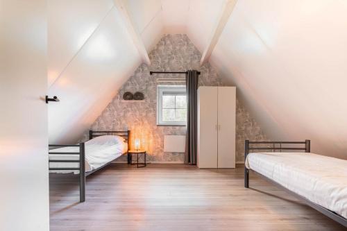 a attic bedroom with two beds and a window at Villa Linde | 4 personen - Vakantiepark De Kremmer in Gasselte