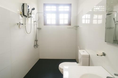 a white bathroom with a toilet and a window at Comfy Stay in Badulla