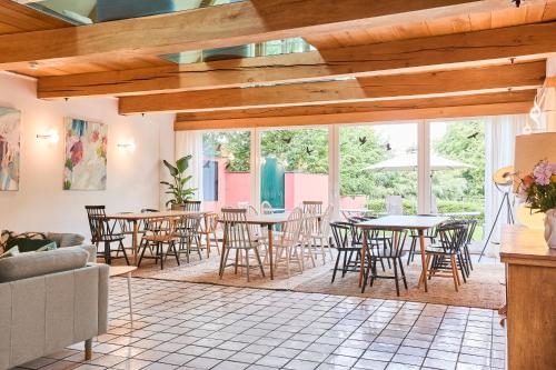 a dining room with tables and chairs and windows at Das Wewelsflether Bäckerhaus - 250qm für 12 Gäste in Wewelsfleth