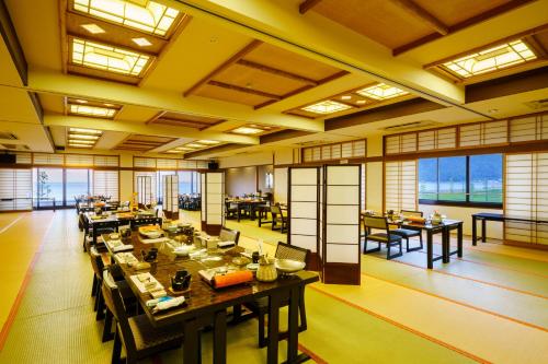 a large dining room with tables and chairs and windows at Seaside Hotel Mimatsu Ooetei in Beppu