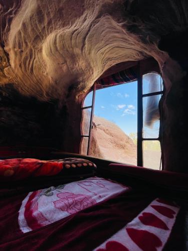 a bed in a room with a view of the desert at Little Petra Bedouin Camp in Al Ḩayy
