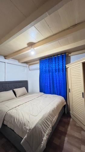 a bedroom with a large bed with blue curtains at Dibi Krui Surf in Krui