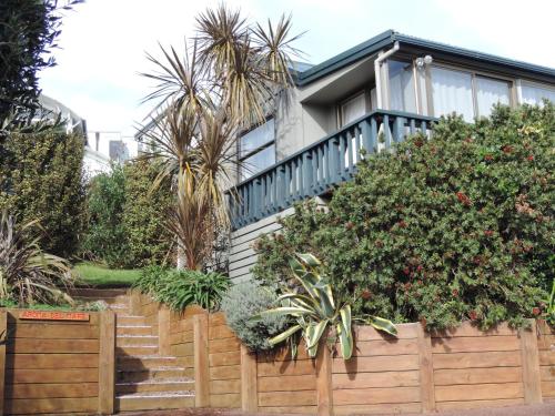 a house with a wooden fence and some plants at Waiheke Island Tawa Lodge - Adults Only in Oneroa