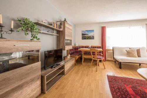 un salon avec une télévision et une table dans l'établissement Chesa Talvo, à Samedan