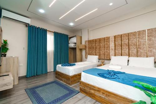 Dos camas en una habitación con cortinas azules. en Sand pyramids hotel, en Giza