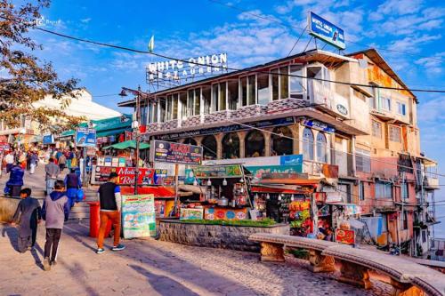 un groupe de personnes se promenant dans un marché avec un bâtiment dans l'établissement Al Maz Hotel Mall Road, à Dargai