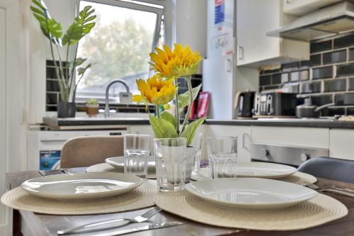 a table with plates and glasses and a vase of flowers at Athol House, near Old Trafford, Free Parking in Manchester