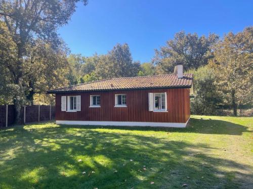 ein kleines rotes Haus in einem Hof mit einem Grasfeld in der Unterkunft Bruyeres in Lesperon
