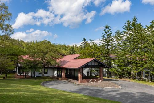 a house with a red roof and a driveway at Yatsugatake Kogen Lodge in Minamimaki