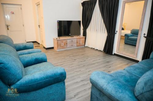 ein Wohnzimmer mit zwei blauen Sofas und einem Fernseher in der Unterkunft King Castle Lake Front By Laksam in Nuwara Eliya