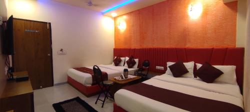 a hotel room with two beds and a red wall at Hotel Avadh Palace, Subhash Bridge, RTO Circle, Ahmedabad in Ahmedabad