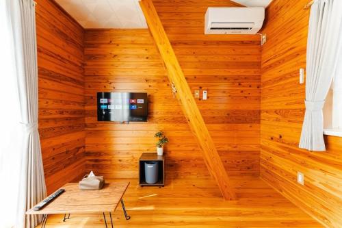 Una habitación con paneles de madera y un televisor en la pared. en 長崎観光の拠点に最適グラバー園近くの一軒家ステイ, en Nagasaki
