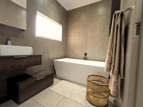 Un baño con bañera, lavabo y ventana. en 40 On Jacopever, en Richards Bay