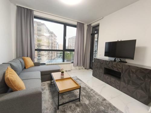 a living room with a gray couch and a flat screen tv at Vitosha view Mladost apartment in Sofia