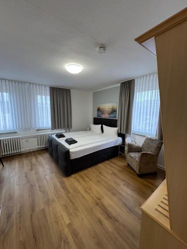 a large room with a bed and a chair at Pension Bertramshof in Wismar
