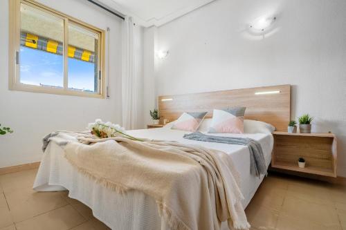 Un dormitorio con una cama con sábanas blancas y una ventana. en Apartamentos ALBENIZ - La Pineda Platja, en La Pineda