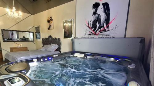 eine Badewanne in einem Zimmer mit einem Bett in der Unterkunft La discrète romantique, appartement avec jacuzzi in Charavines