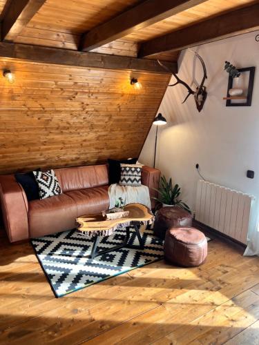 ein Wohnzimmer mit einer Ledercouch und einem Tisch in der Unterkunft Chalet A Baisoara - Piscină încălzită - Pârtii în apropiere in Băişoara