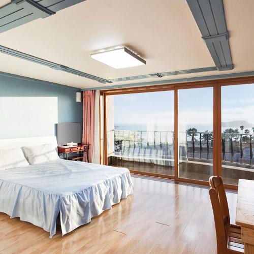 a bedroom with a bed and a large window at Jeju Castle in Seogwipo